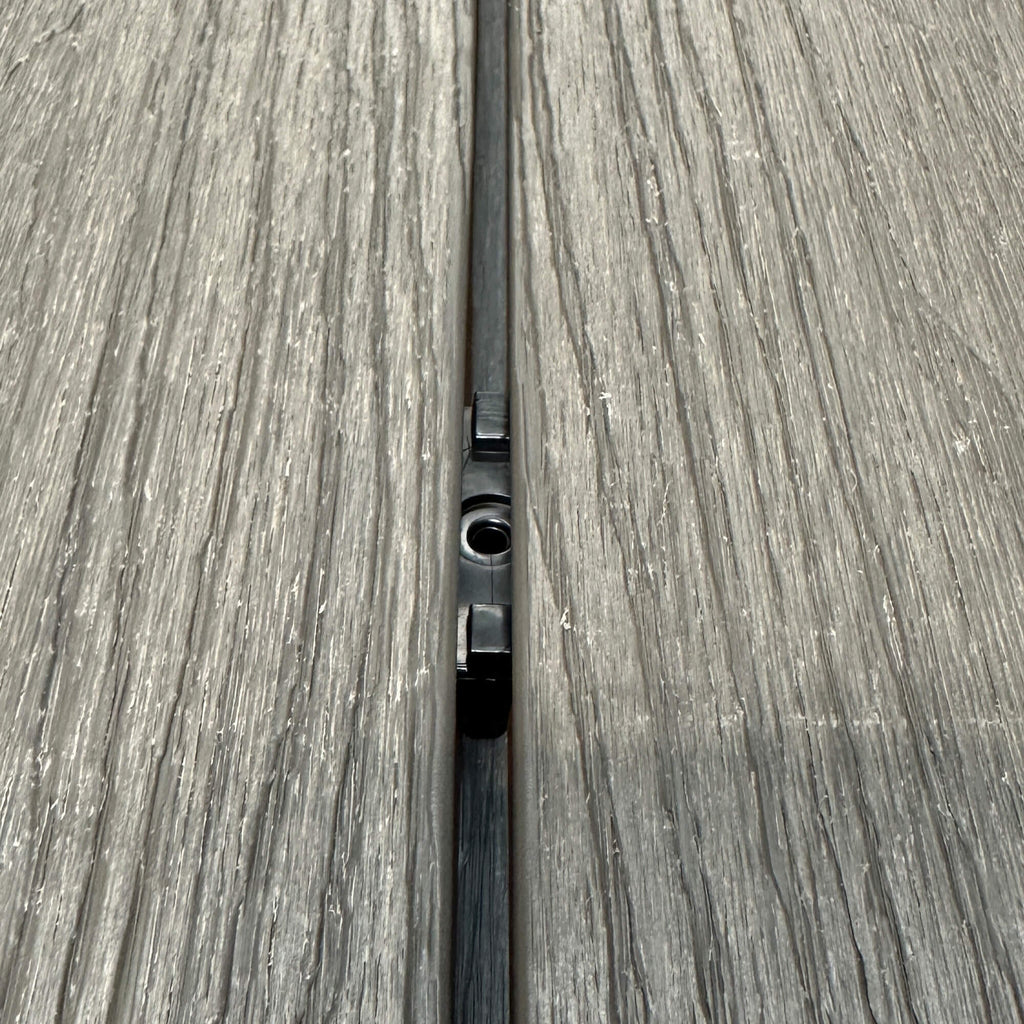 A Black Decking Clip in situ on a decking patio background.