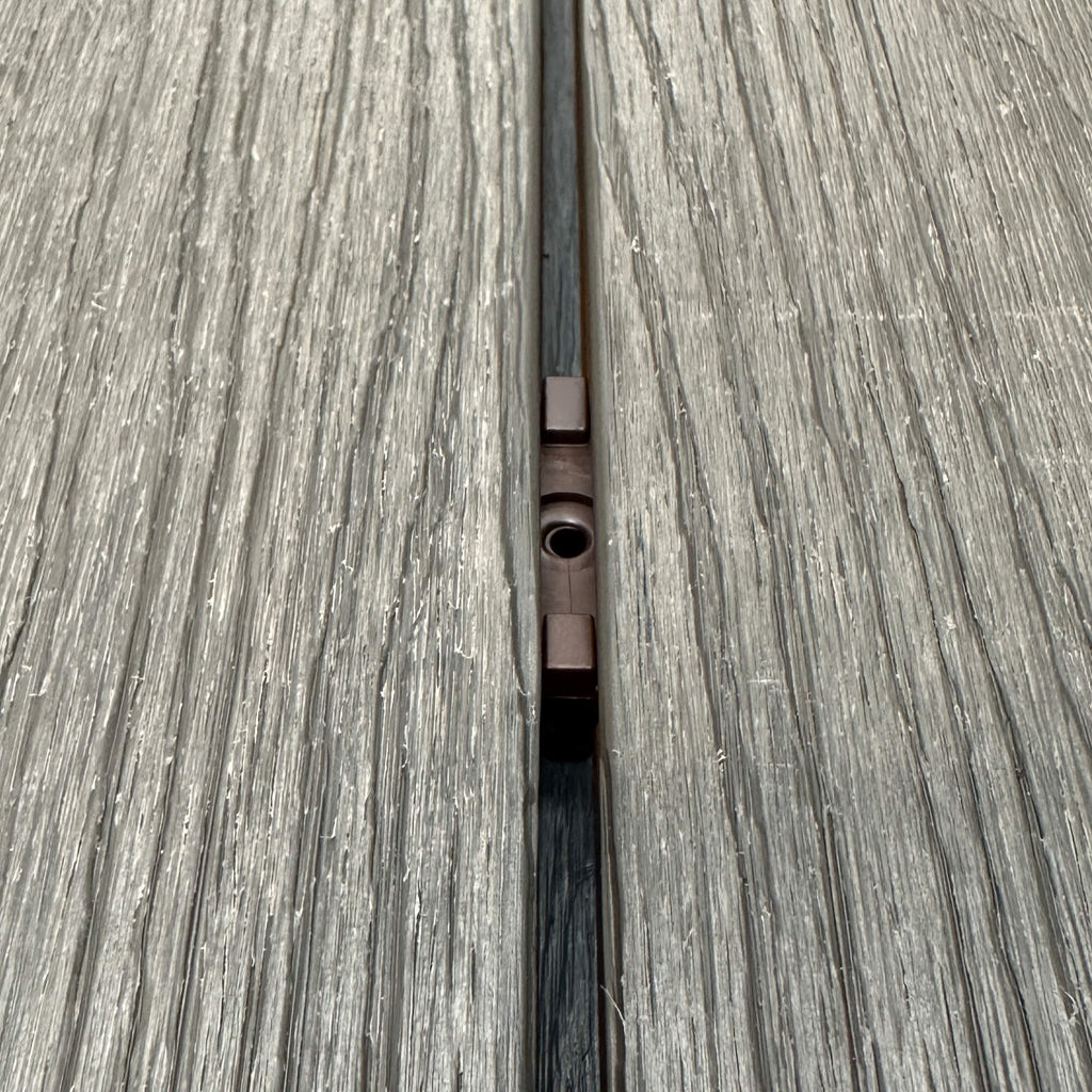 A Brown Decking Clip in situ on a decking patio background.