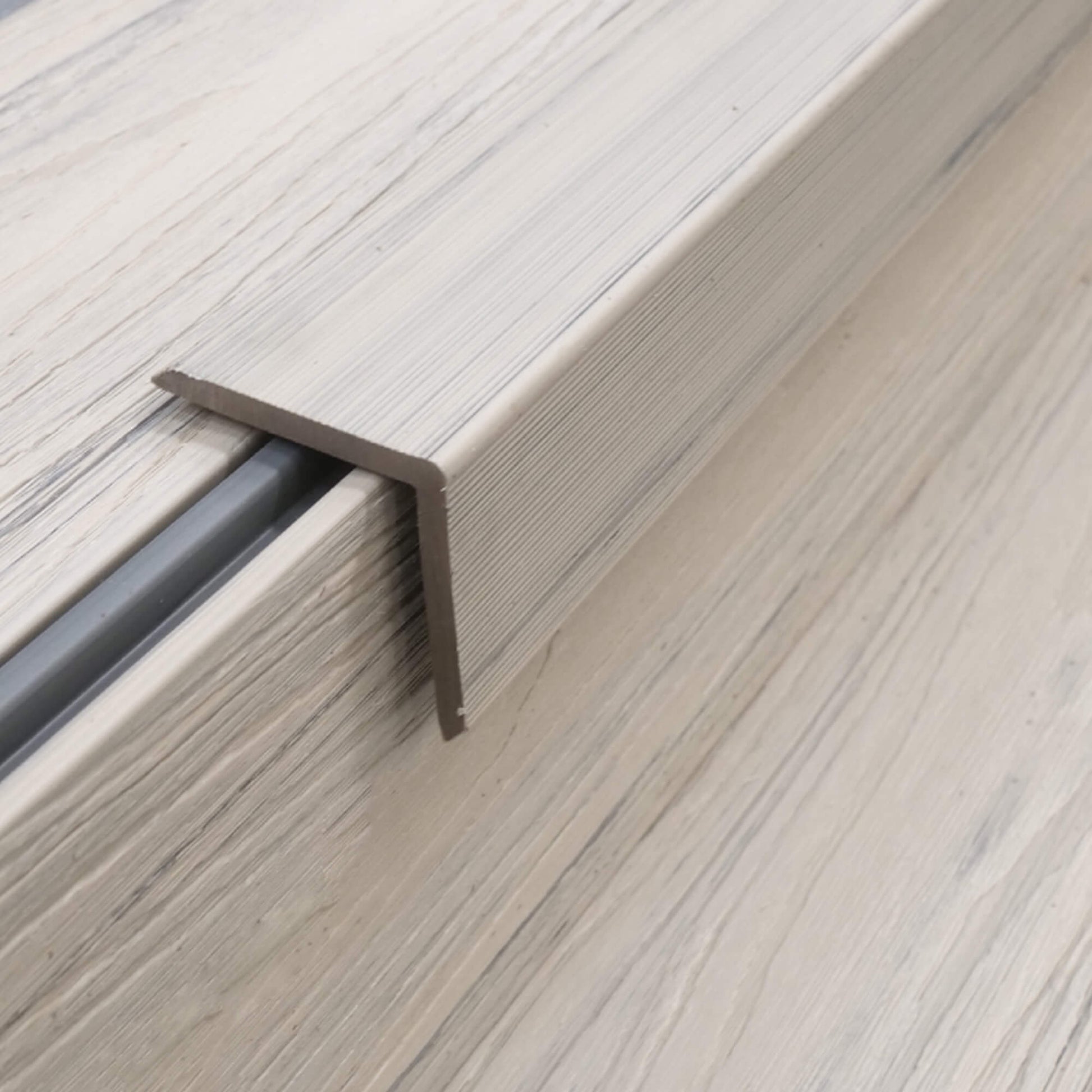 An Ivory Co-Extruded Composite Cover Strip in situ on decking on a patio.