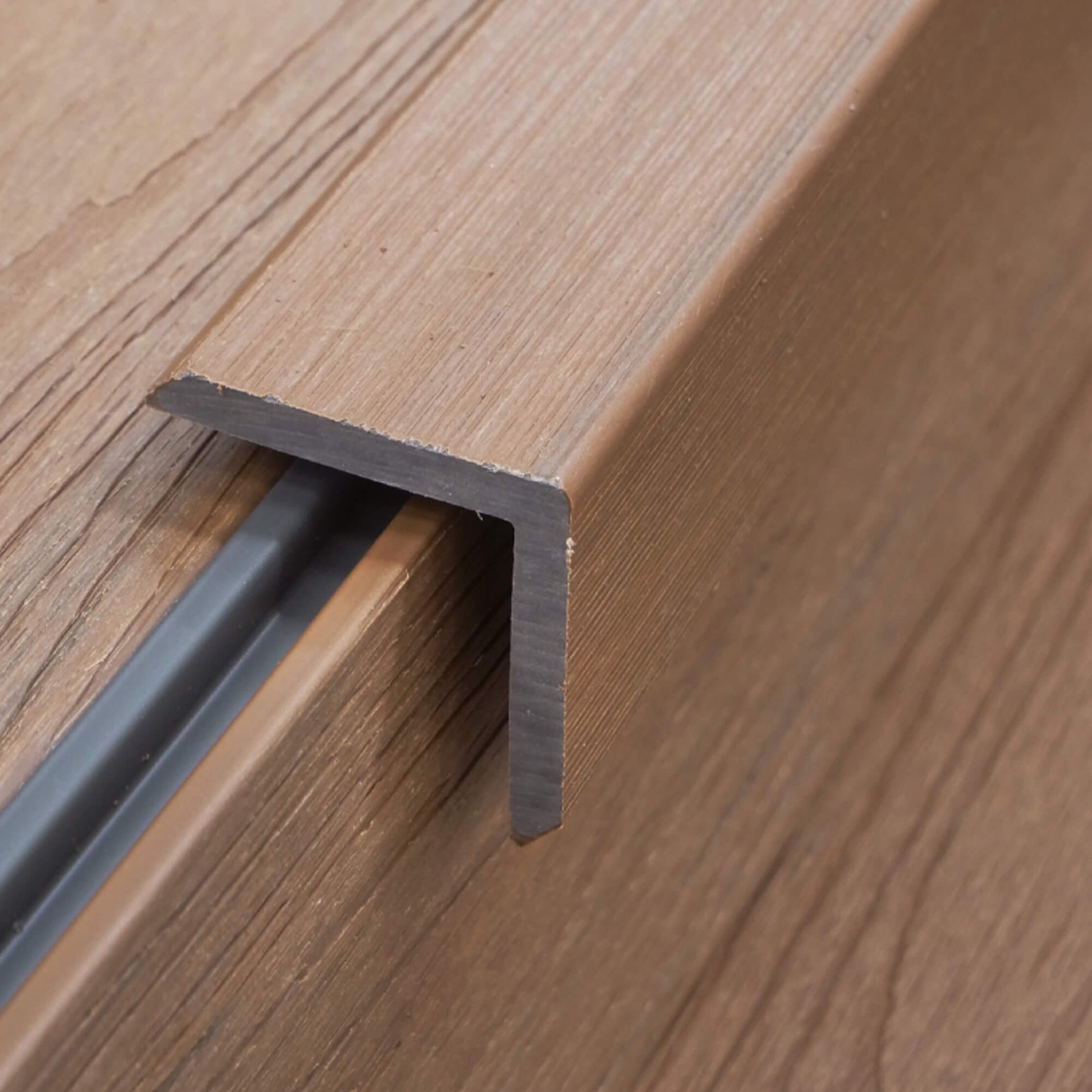 A Teak Co-Extruded Composite Cover Strip in situ on decking on a patio.