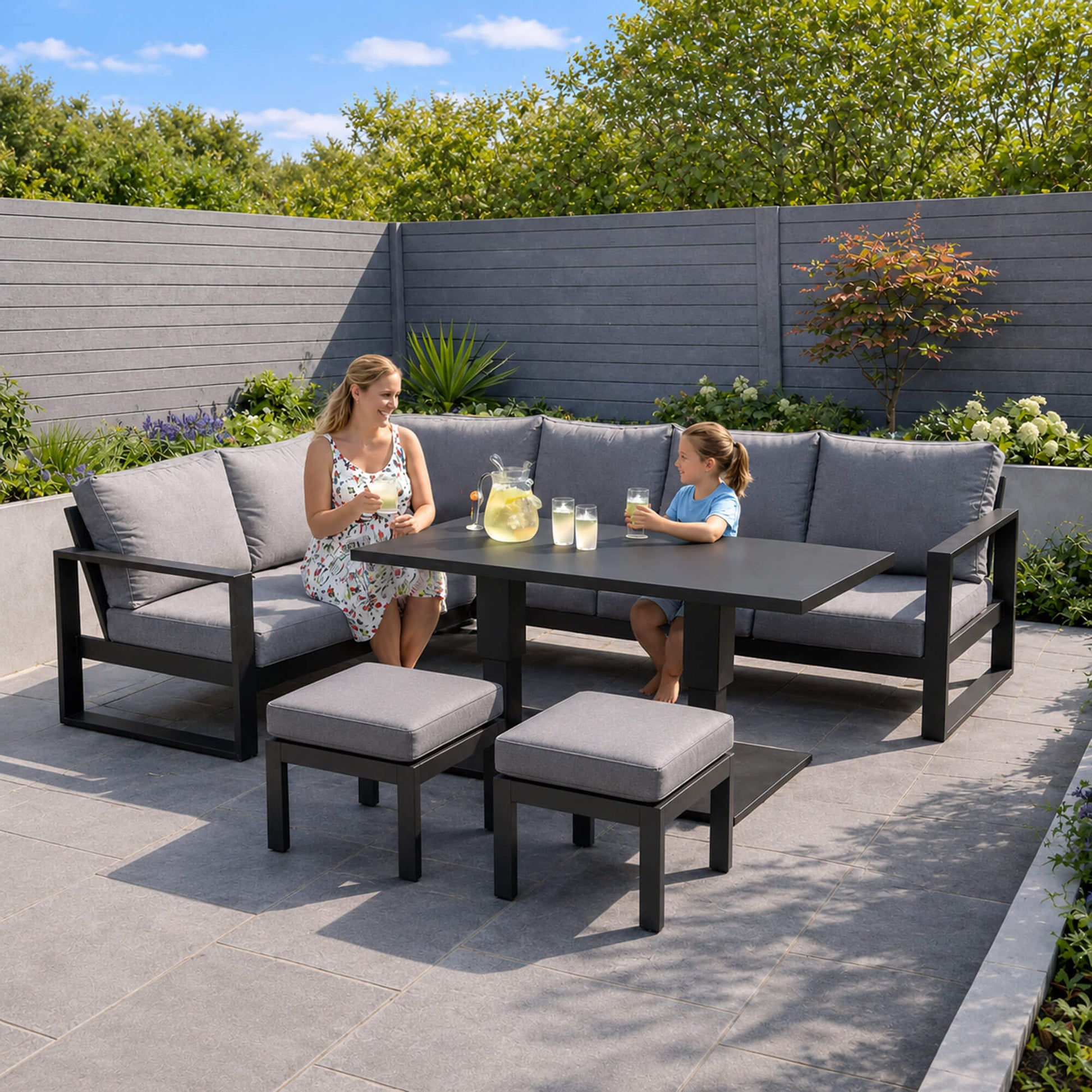 Mother and daughter sitting on a Como corner set with outdoor furniture in a garden setting.