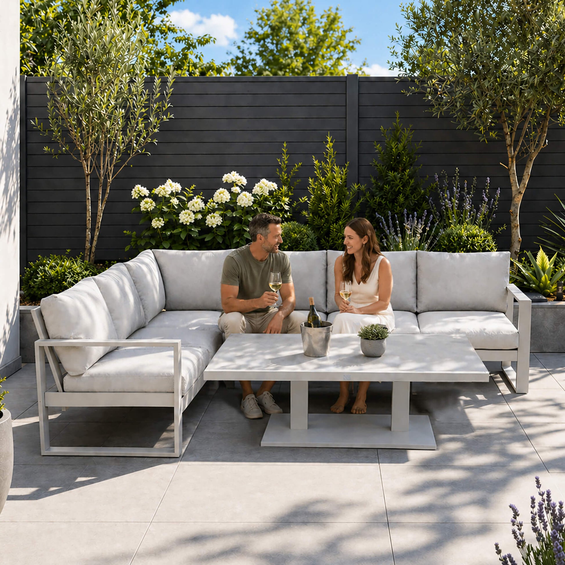 A couple sitting on a Como L-Shaped outdoor furniture corner set in a patio setting.