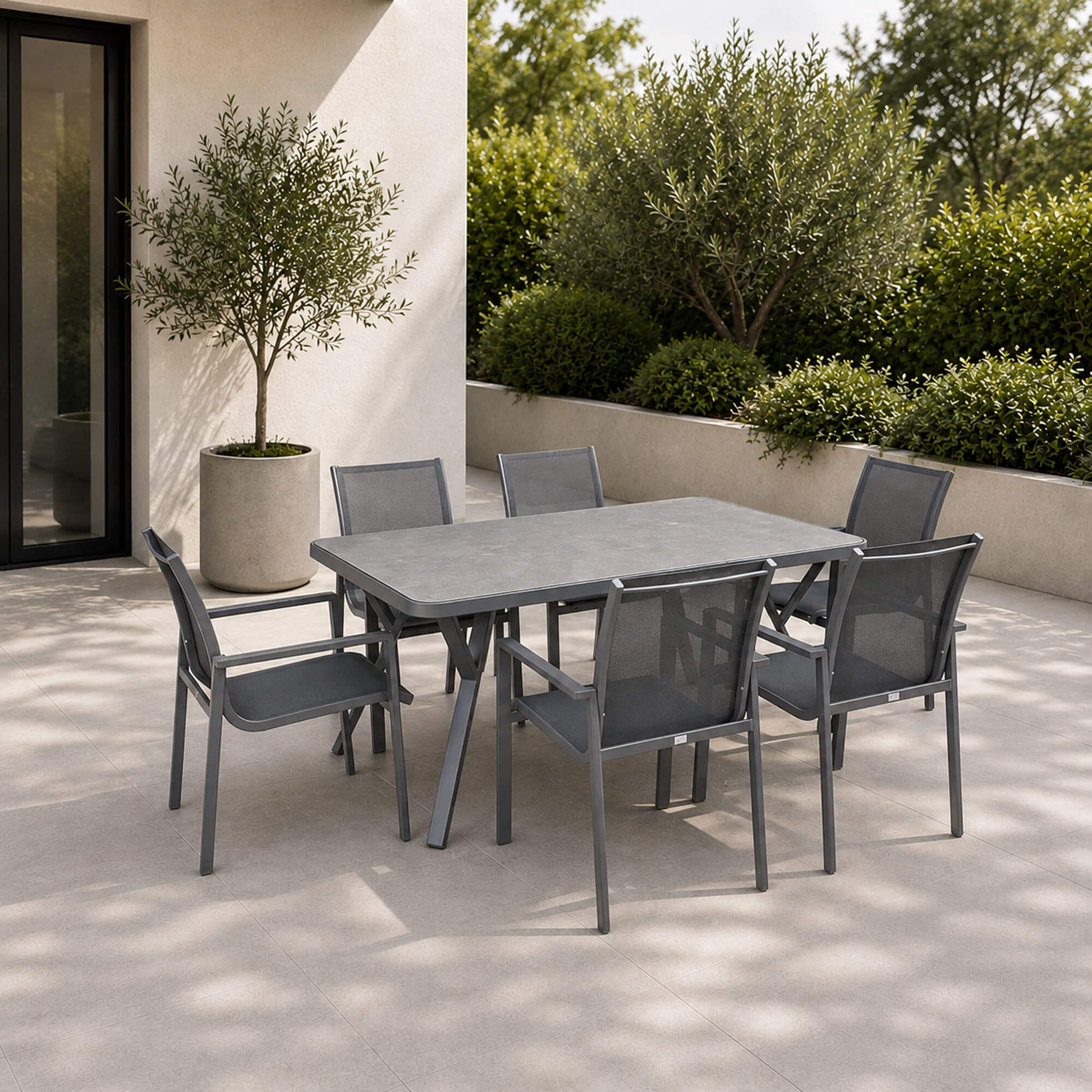 The Garda dark grey outdoor dining set positioned on a concrete patio in a modern garden setting.